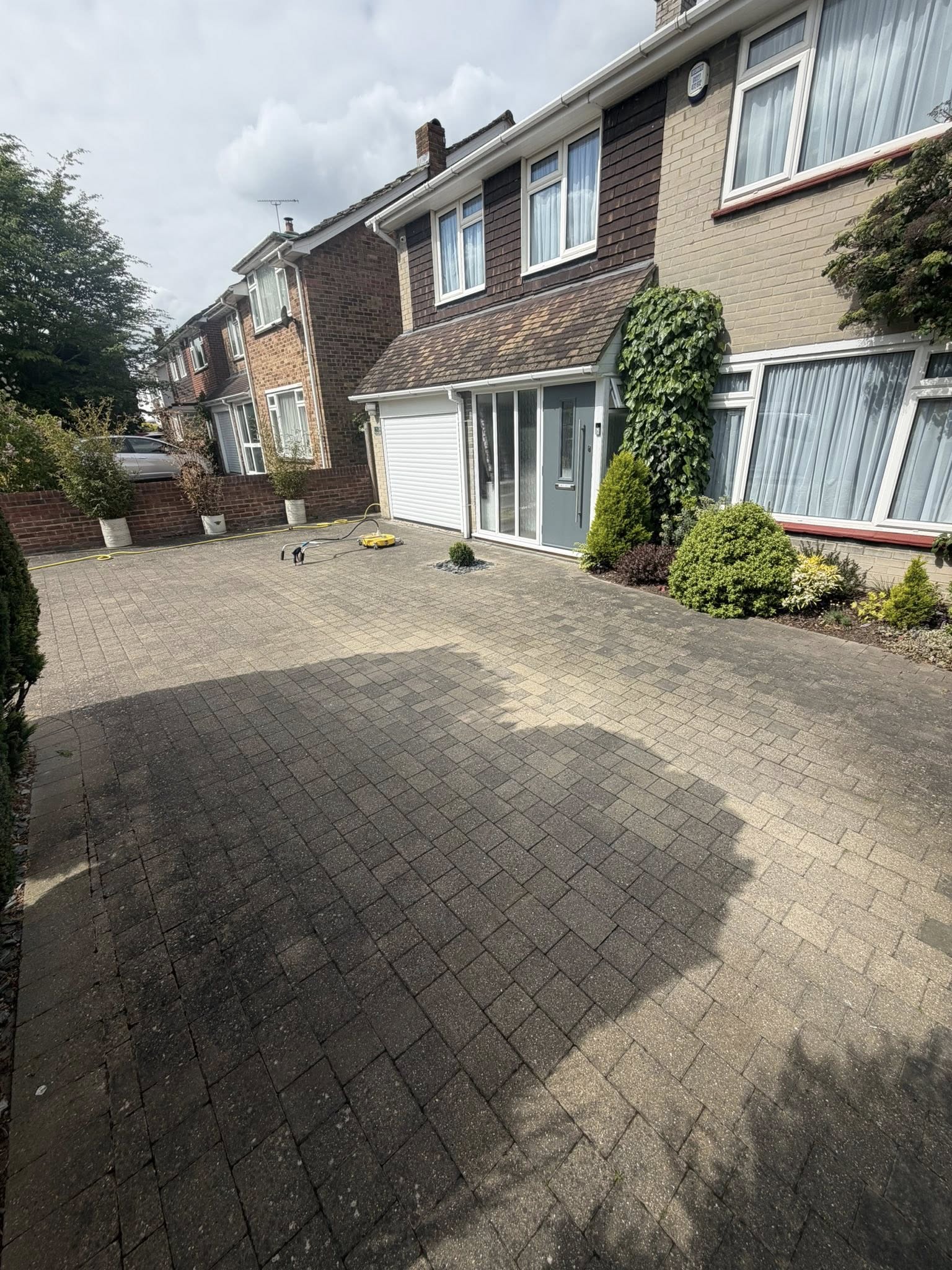 Clean driveway and house exterior with landscaping