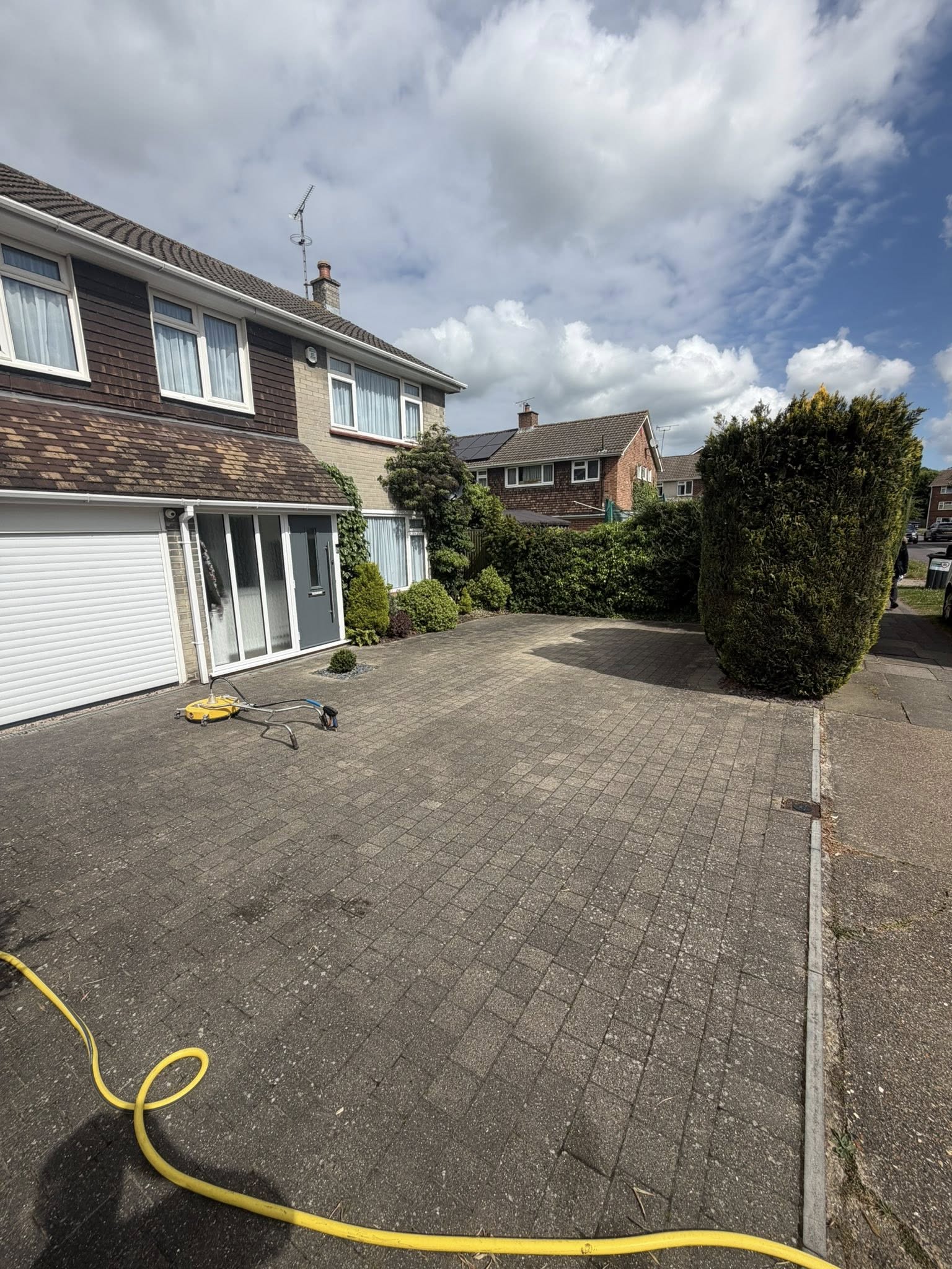 Driveway being cleaned with pressure washer equipment